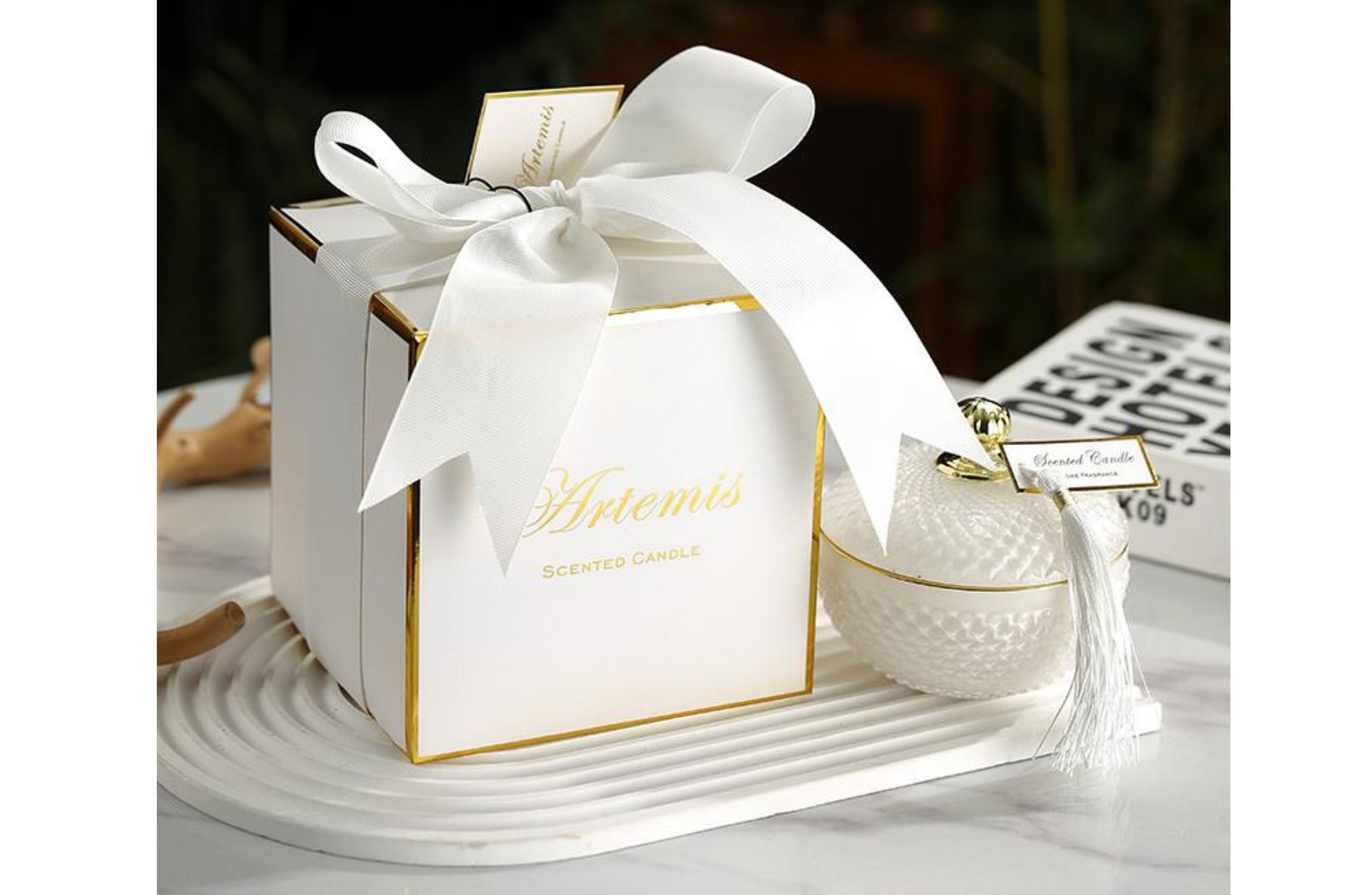 Artemis luxury candle in a textured white glass jar with tassel lid, scented with jasmine and white rose, packaged in an elegant white gift box.