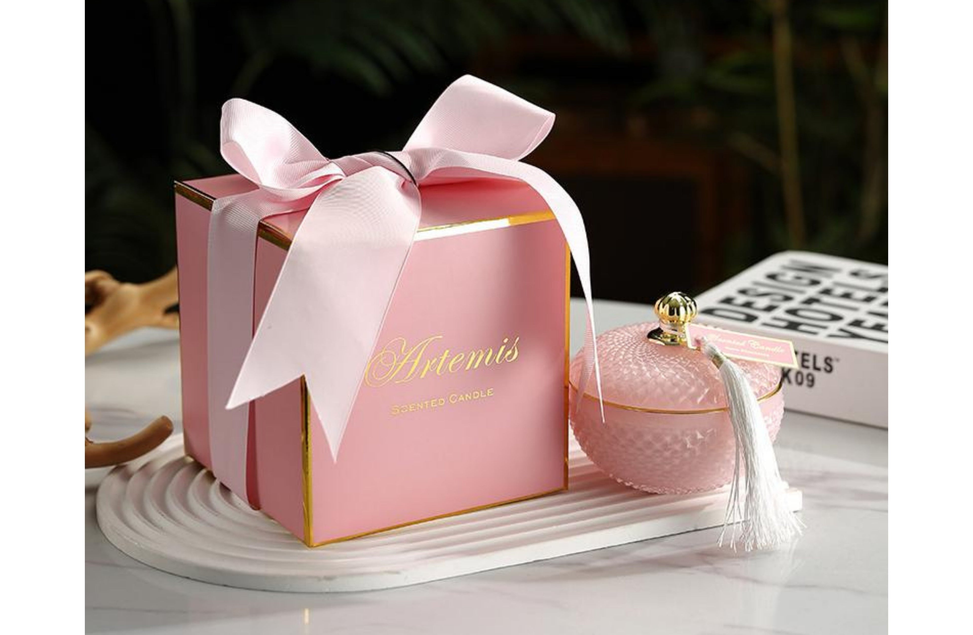 Artemis luxury candle in a textured light pink glass jar with tassel lid, scented with sweet caramel, beautifully packaged for gifting.