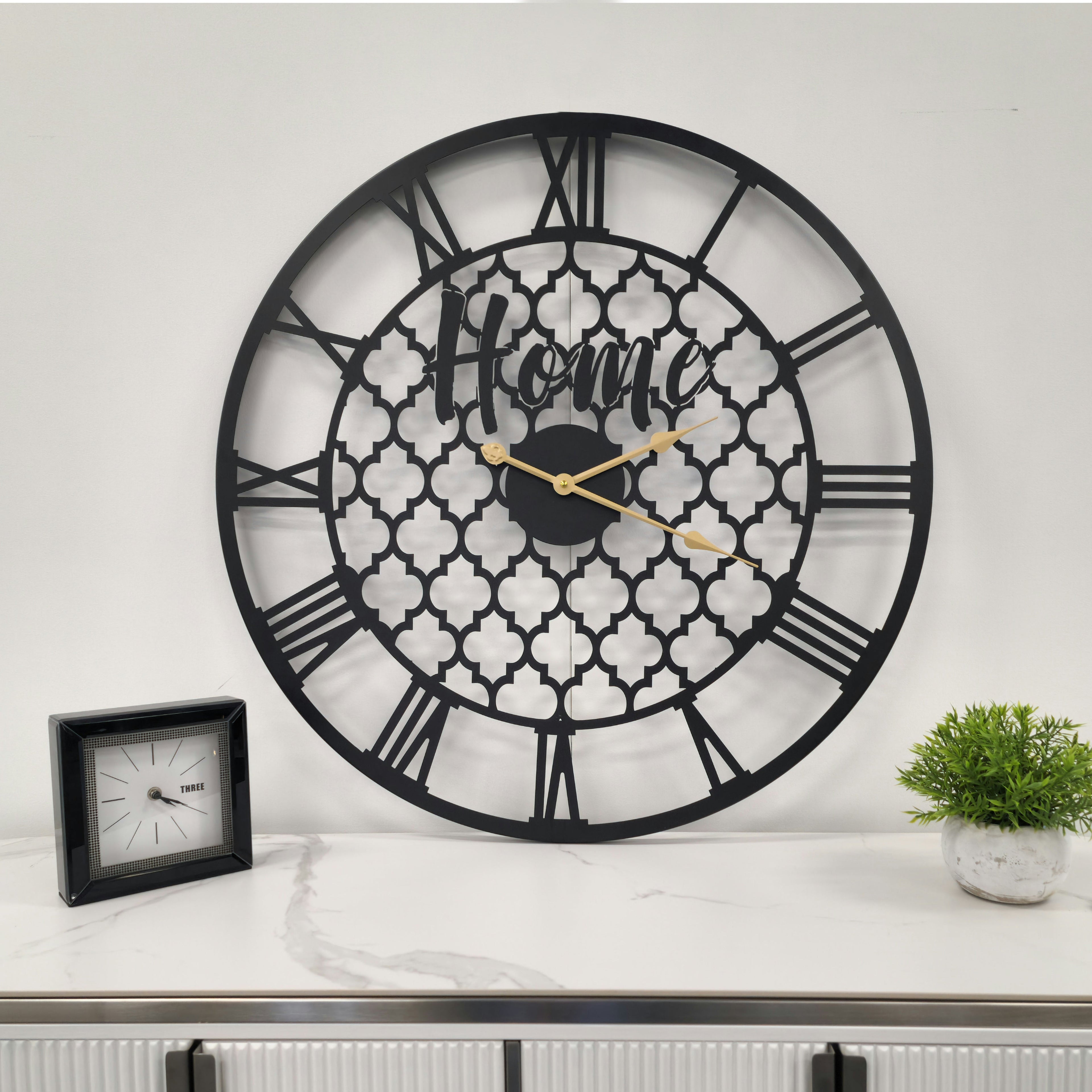 Black quatrefoil wall clock styled above console table, contemporary and elegant decorative timepiece.