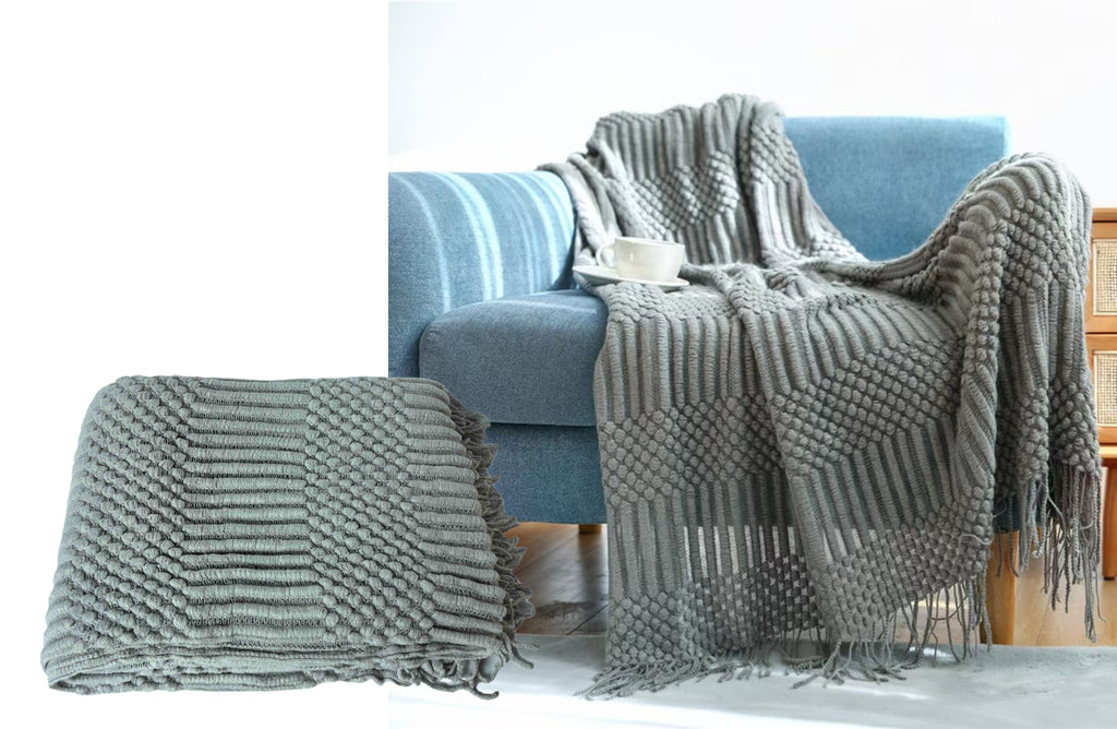 Folded grey Tessa throw rug blanket with plush textured design and delicate fringe detail.