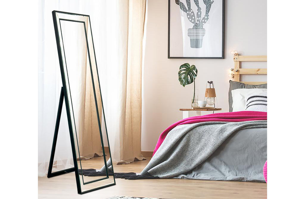 Free standing black beaded framed mirror styled in bedroom with modern décor.