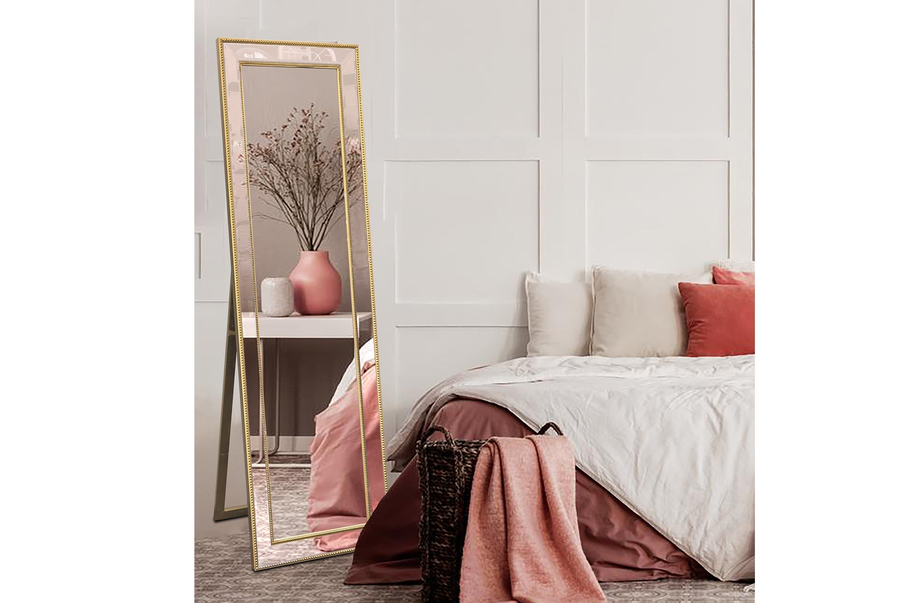 Free standing gold beaded framed mirror styled beside bed with soft décor.