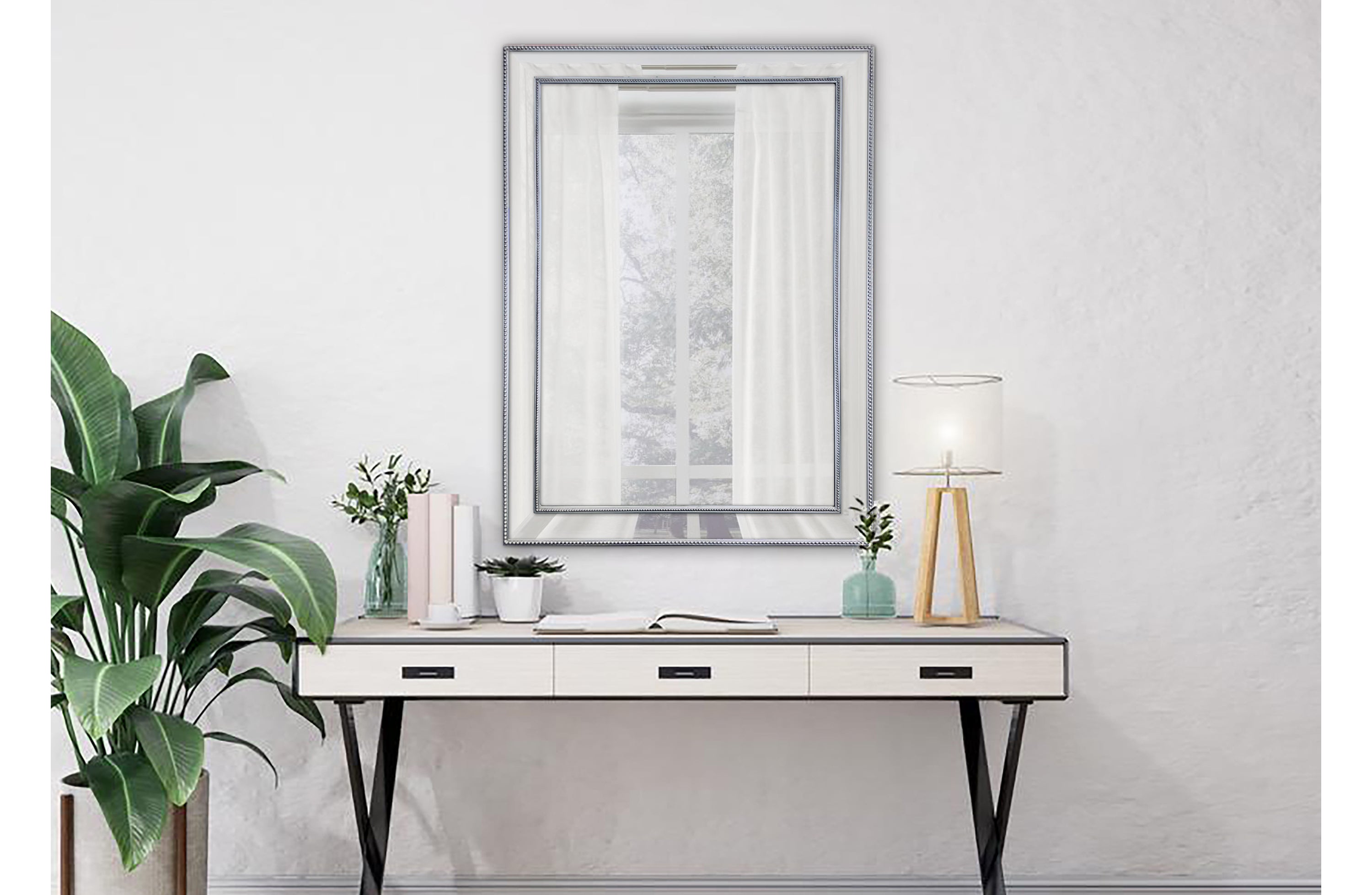 Small silver beaded framed mirror styled above desk with indoor plants.