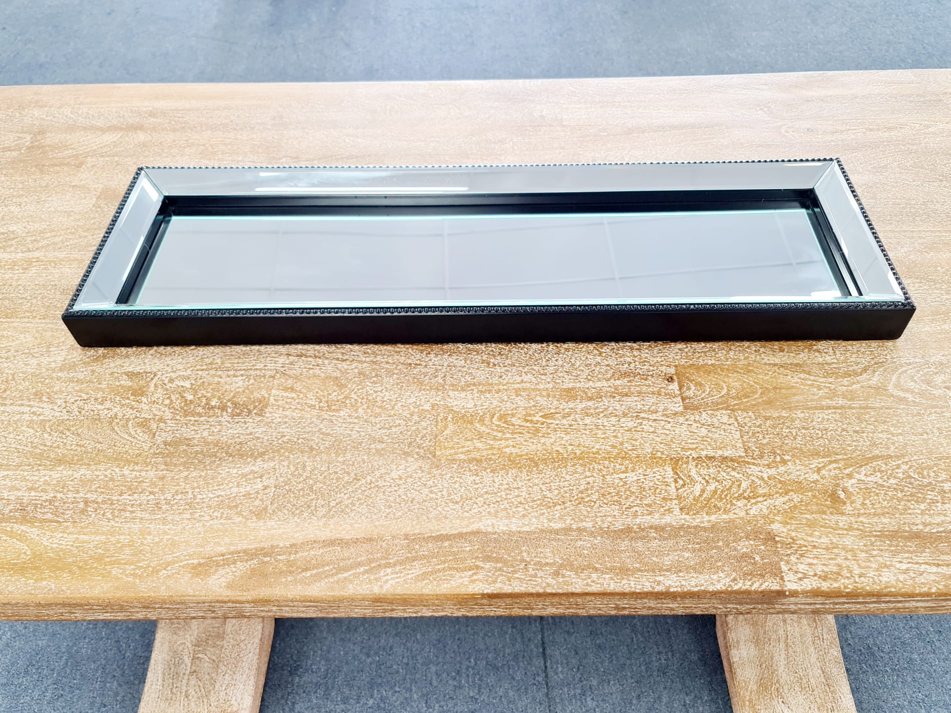 Modern black beaded mirror tray on wooden table – elegant & stylish.