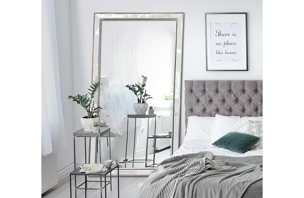 Beaded extra large silver framed mirror styled in modern bedroom with bed and side tables.