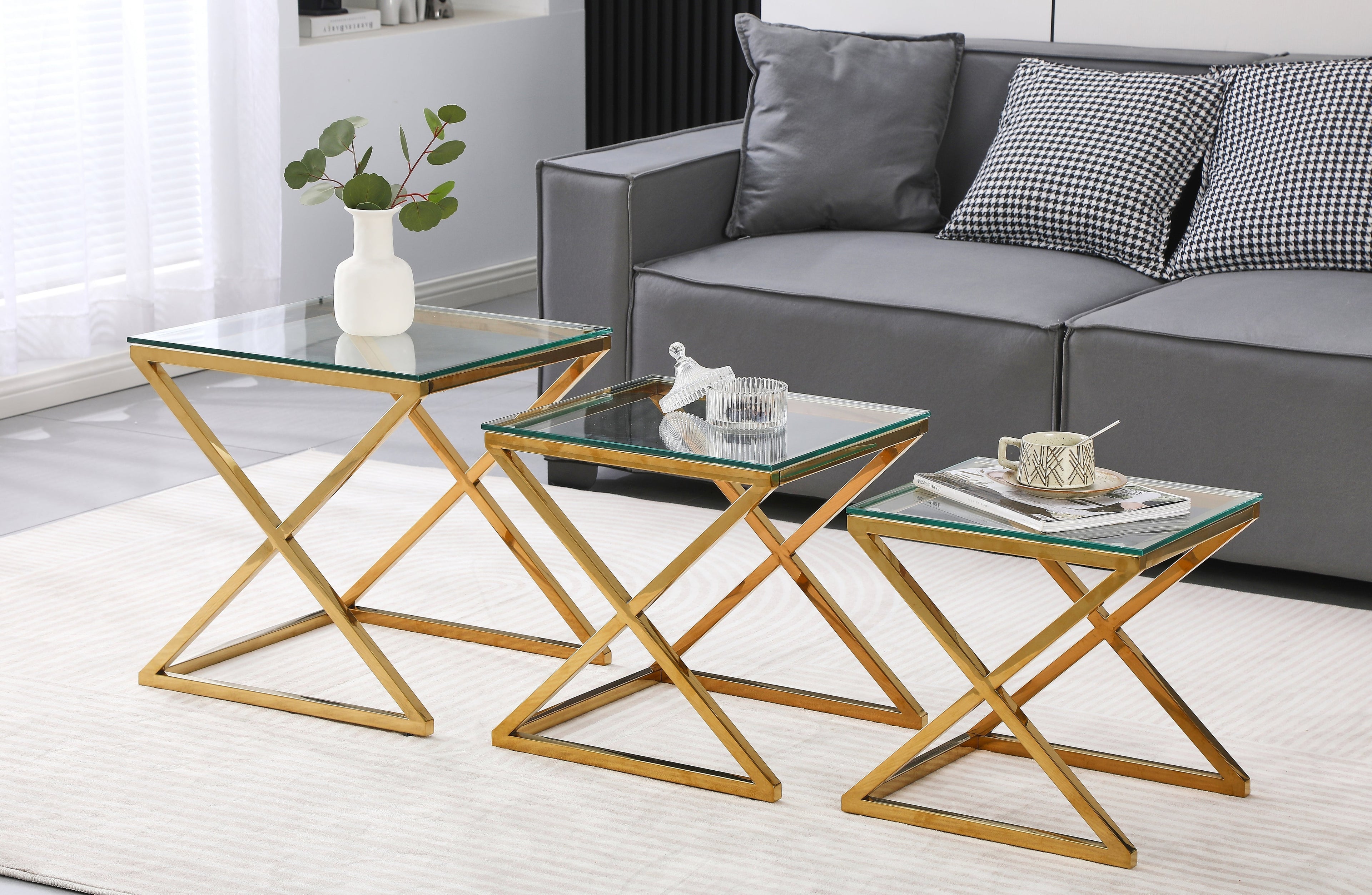 Bella set of three nesting side tables with polished gold frame and clear glass tops in lounge.