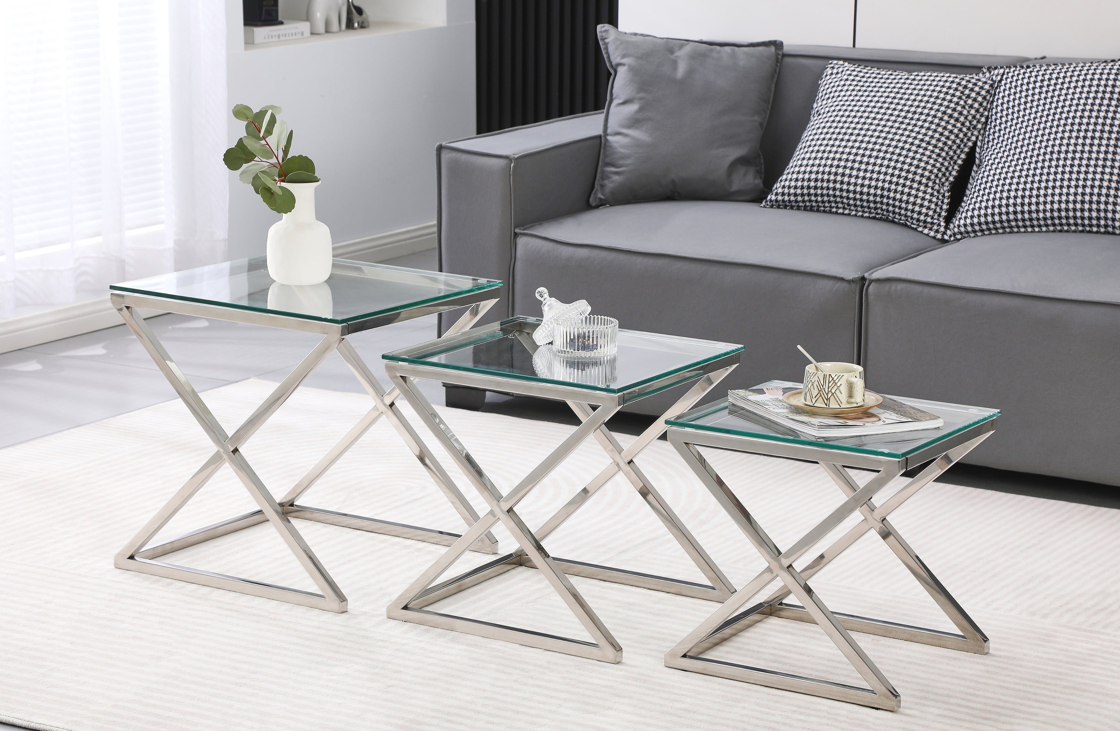Bella set of three side tables with polished silver frame and clear glass tops in lounge.