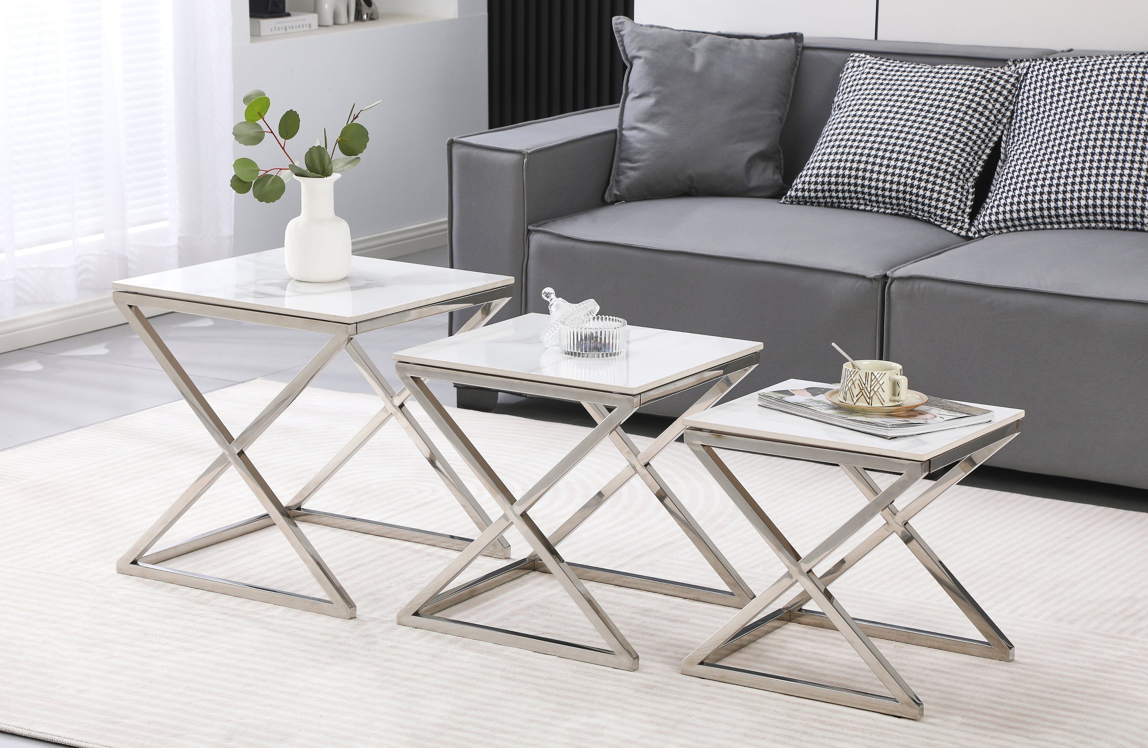 Bella nesting side tables in polished silver frame with white marble tops, styled in living room.