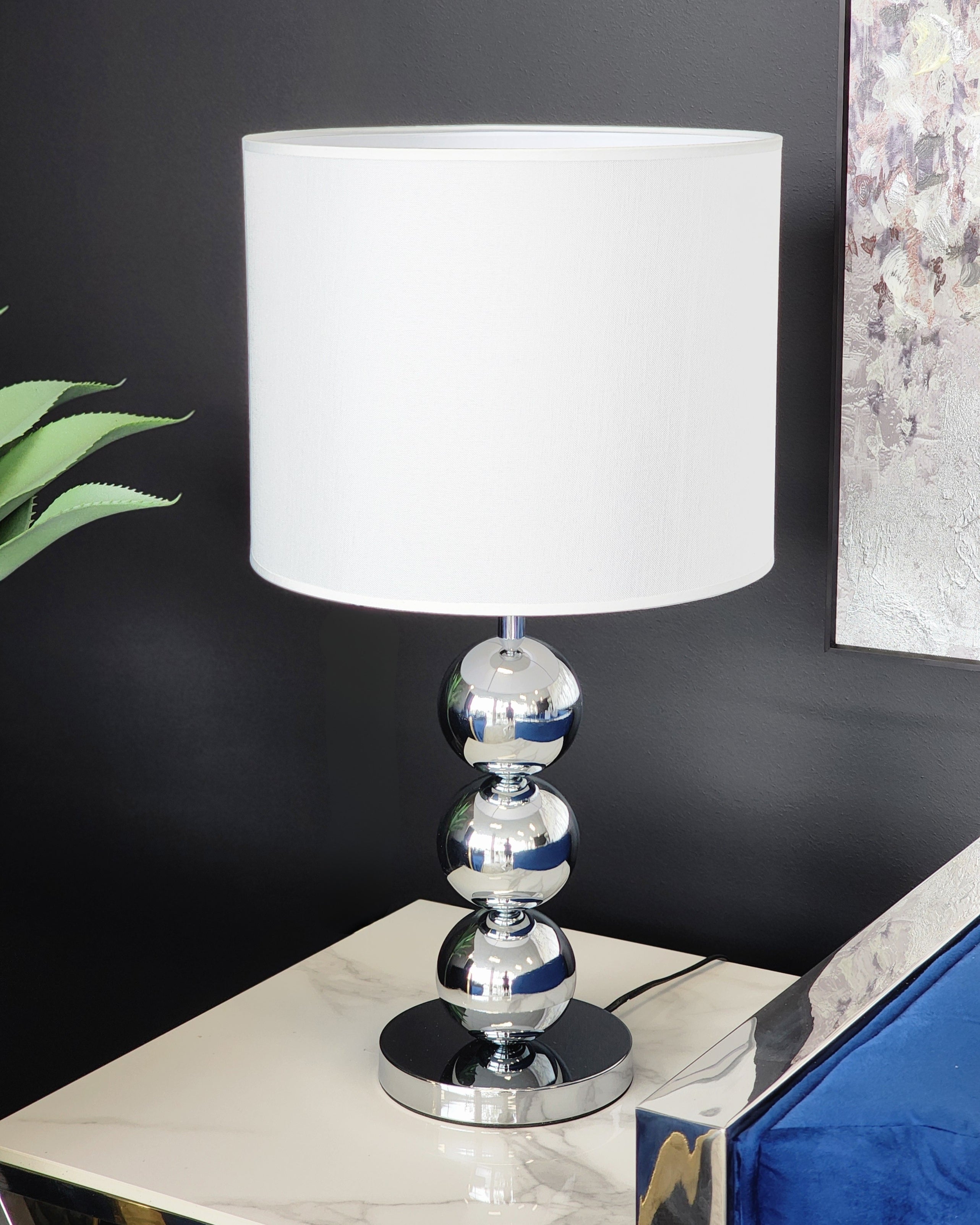Beth Table Lamp with silver base and white shade styled on side table in modern décor