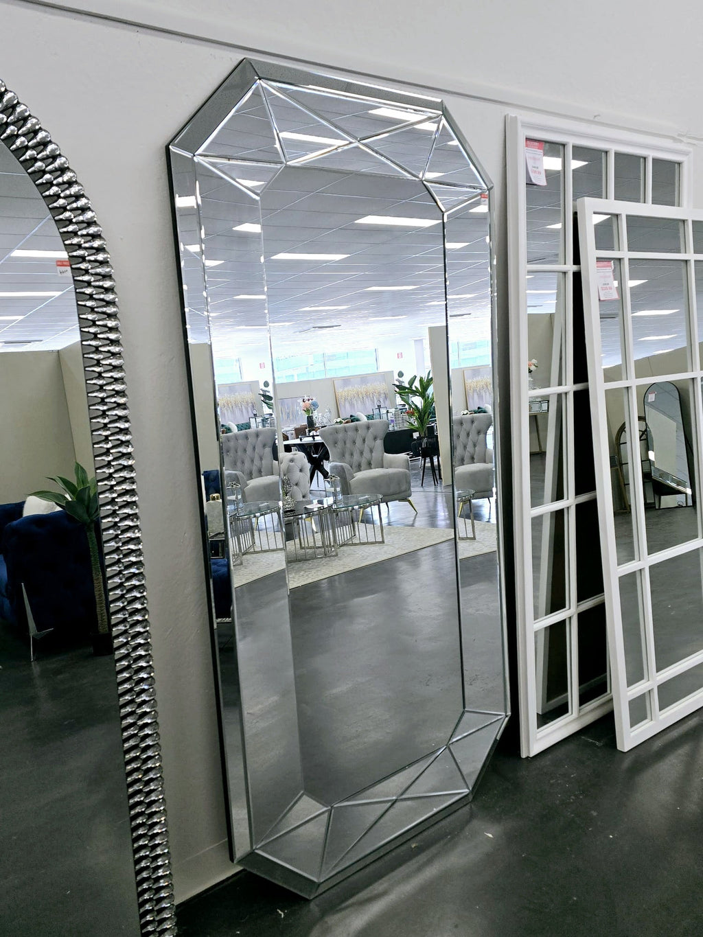 Contemporary geometric full-length mirror styled in showroom with other luxury mirrors