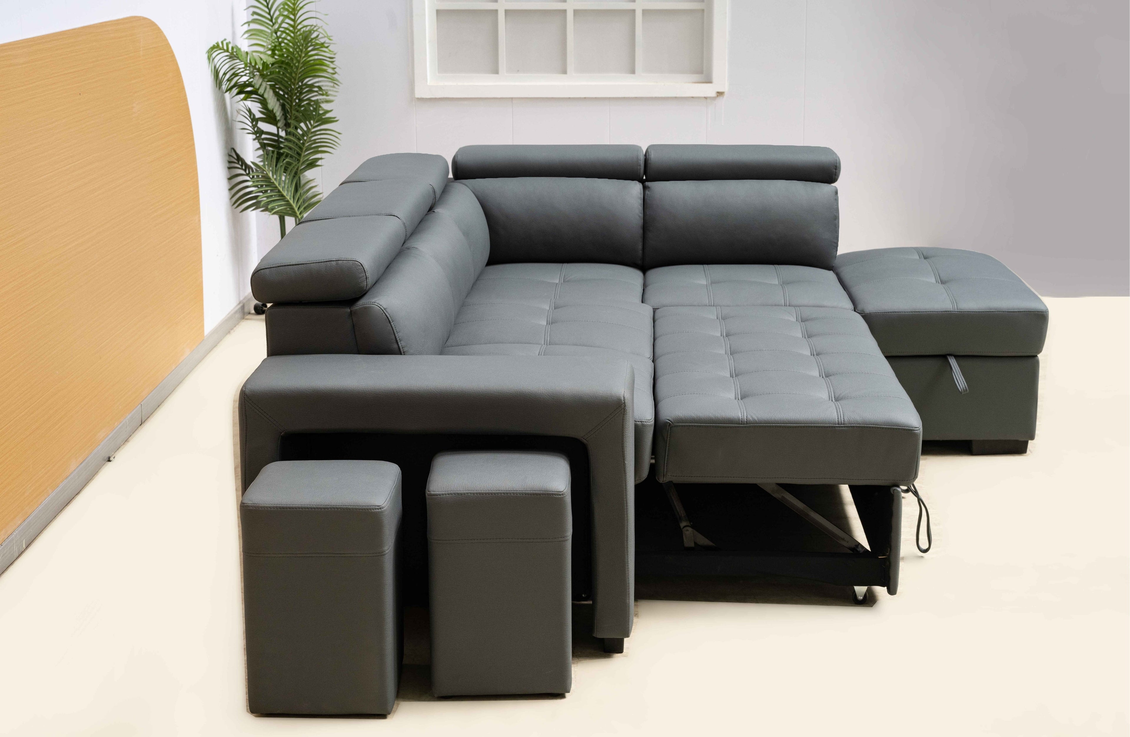 Dark grey Hamilton modular chaise lounge styled in room, extended bed and ottoman storage open.