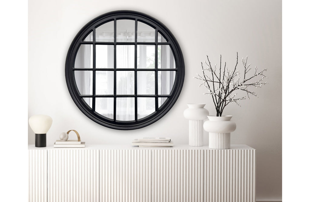Black Hampton's round window mirror styled above a console table in modern living room.