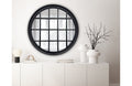 Black Hampton's round window mirror styled above a console table in modern living room.