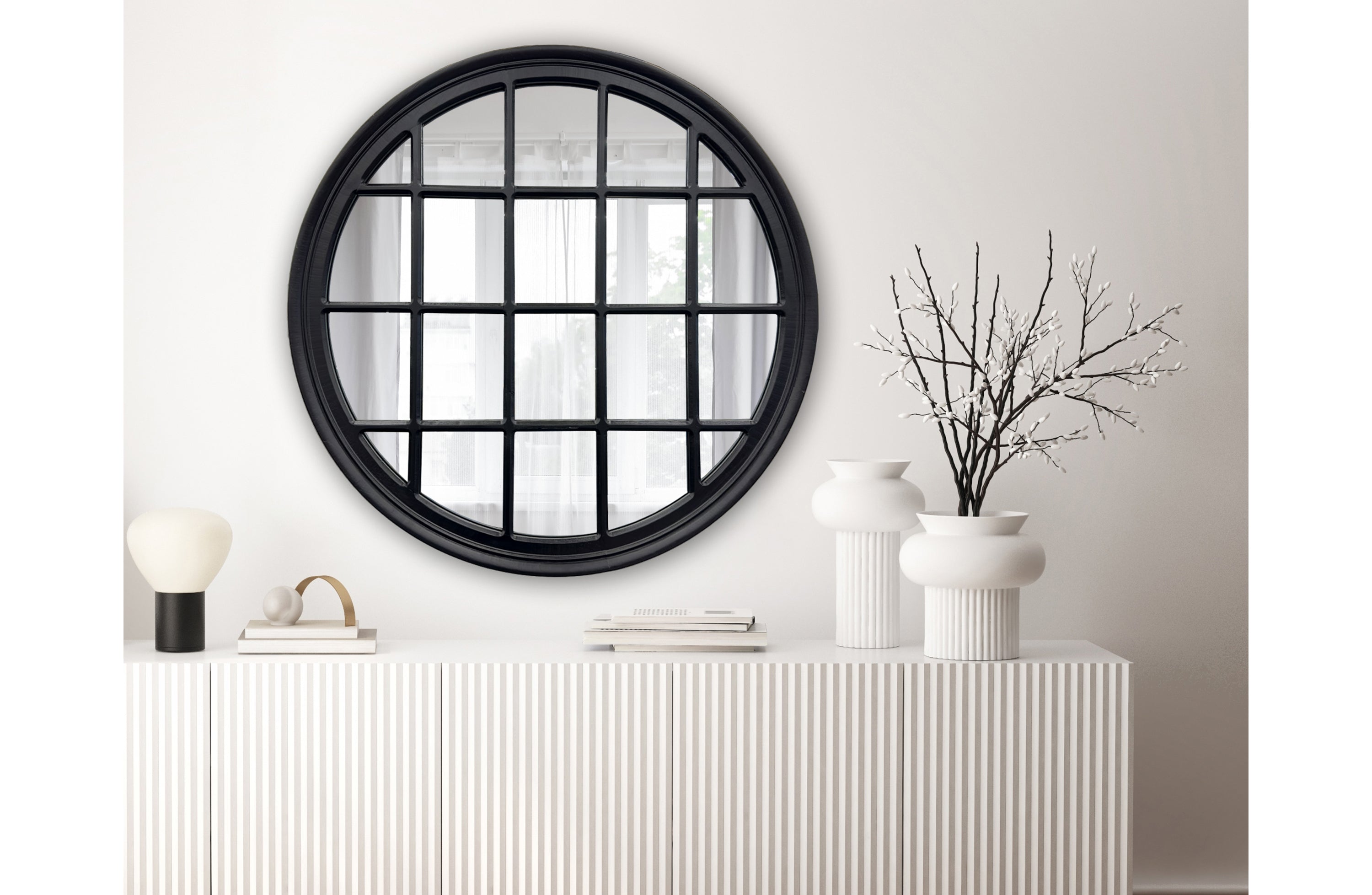 Black Hampton's round window mirror styled above a console table in modern living room.