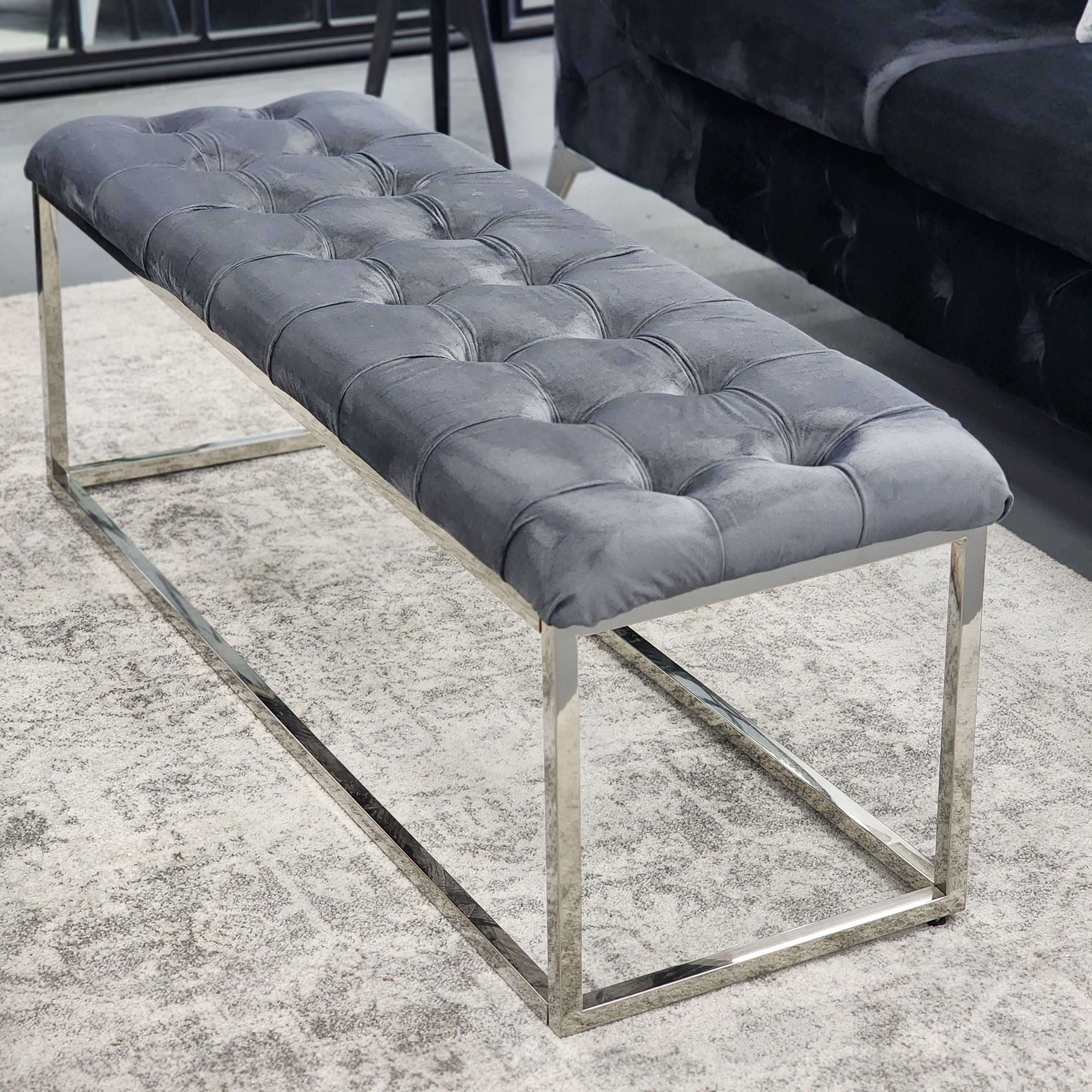 Angled view of Grey Holly Ottoman Bench with silver frame and tufted velvet upholstery.