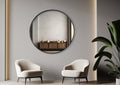 Black round wall mirror styled above modern lounge with two armchairs