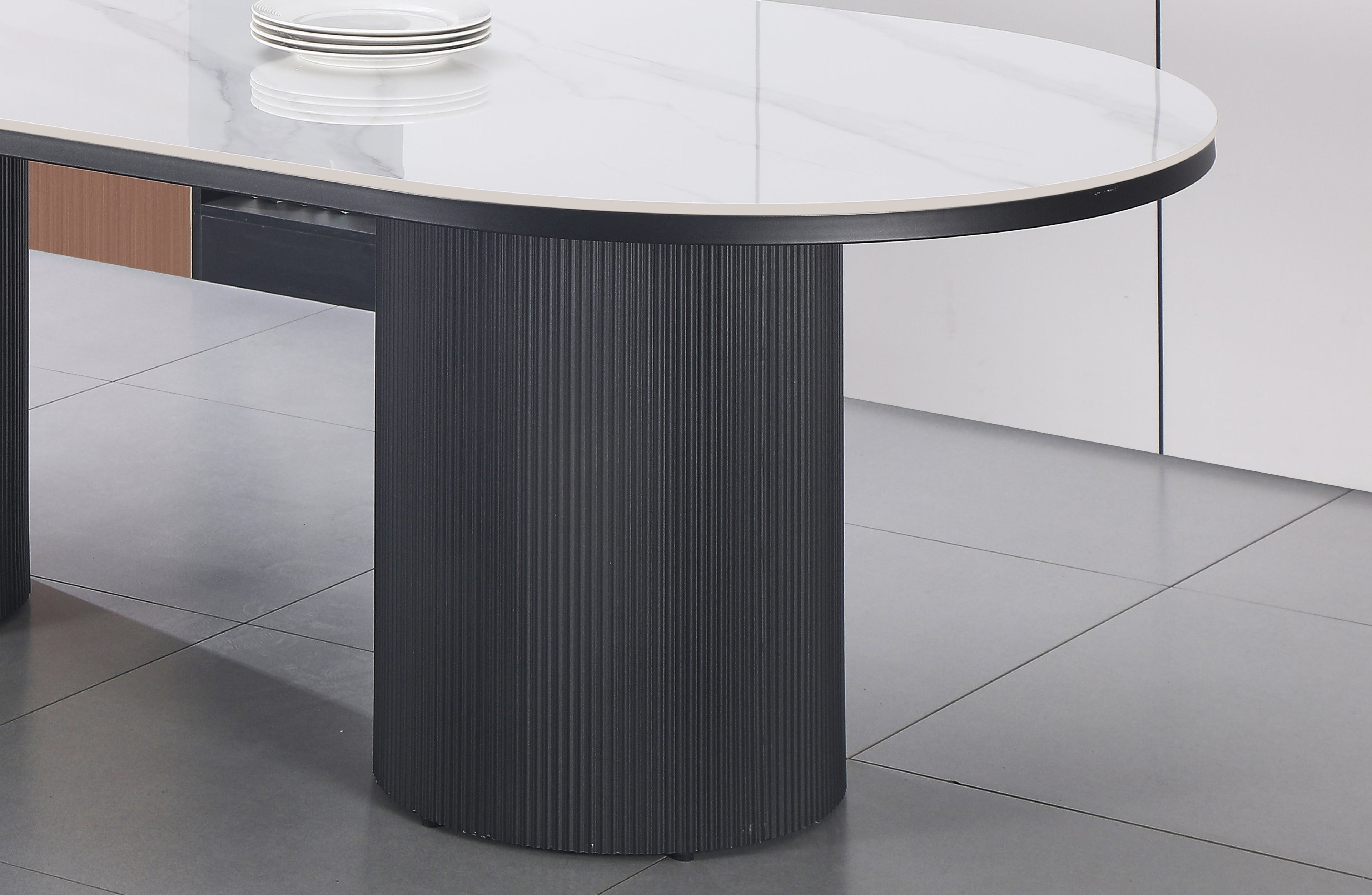 Close-up of Ripple Oval Dining Table showing white marble surface and sleek black base.
