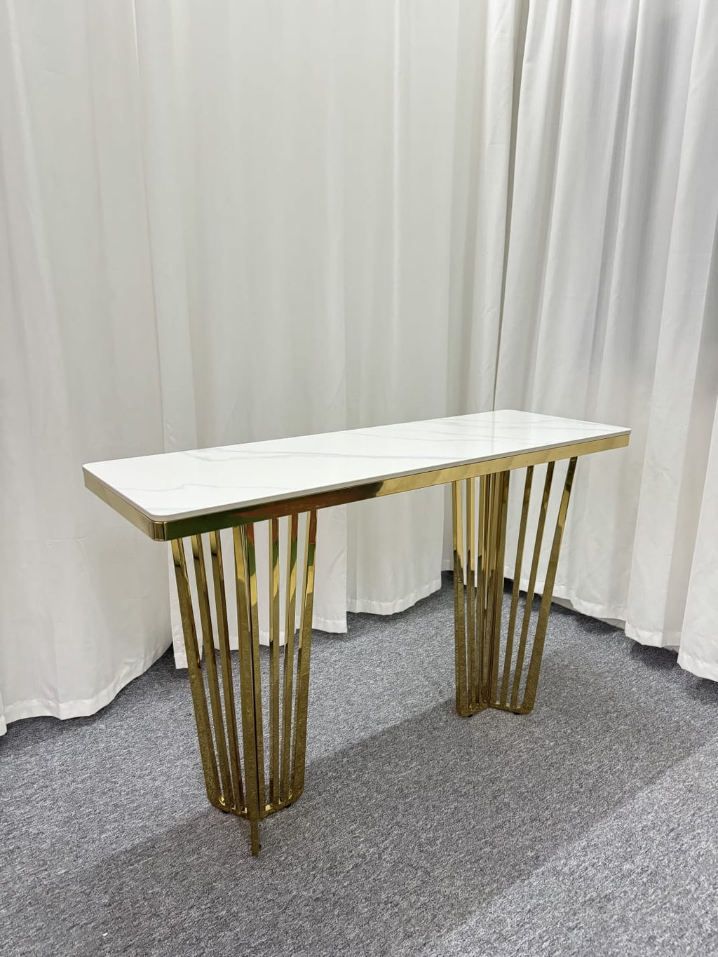 Serena console table with polished gold frame and white marble top in studio setting.
