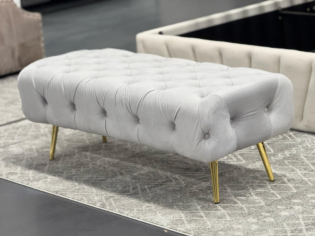 Light Grey Shirley Ottoman with gold frame and tufted velvet top, elegant lifestyle setting.